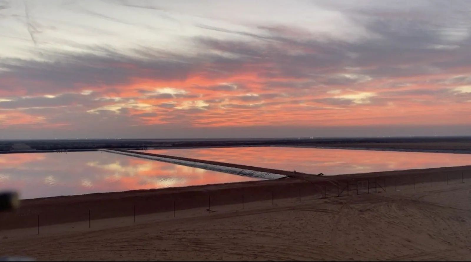 Large lined water ponds reflecting a red sunset